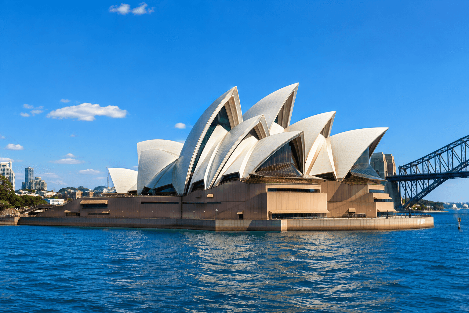 Sydney Opera House beside the harbour under a clear blue sky